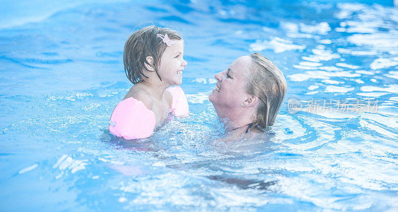 妈妈和她的小女儿快乐地在游泳池里