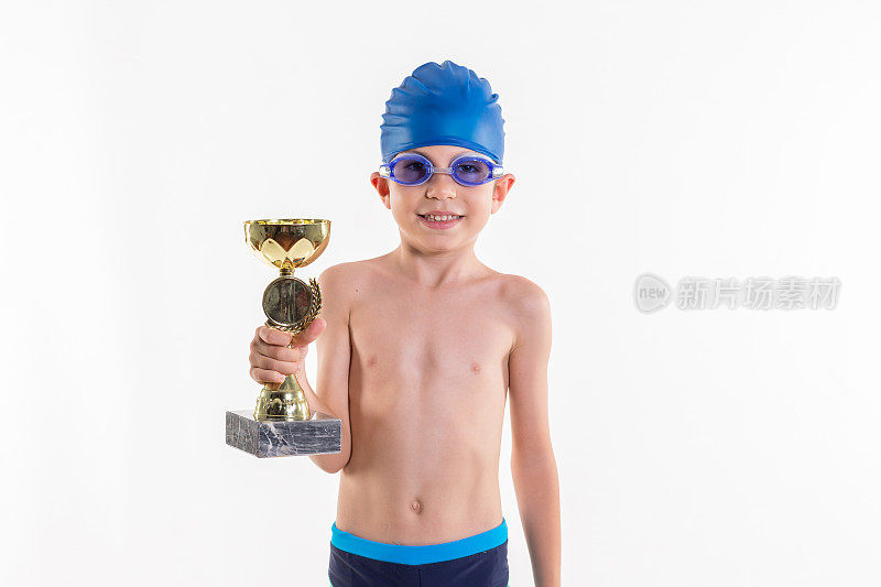 穿着泳衣和泳镜的快乐小男孩在白色背景下赢得了奖杯