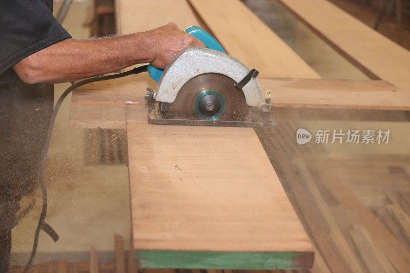 电圆锯是木工车间的高级木匠用手在锯屑上锯出一块木头。