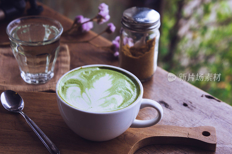 木桌上的绿茶热饮拿铁白杯，香气袭人，咖啡厅休闲时光