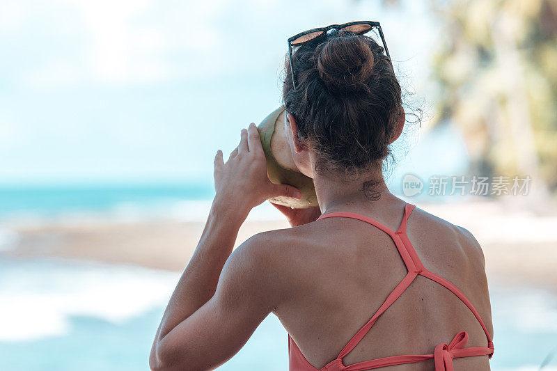 女人喝椰子水和看海浪近距离