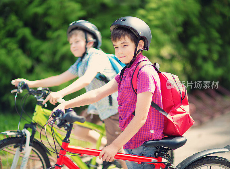 孩子们背着背包在学校附近的公园里骑自行车