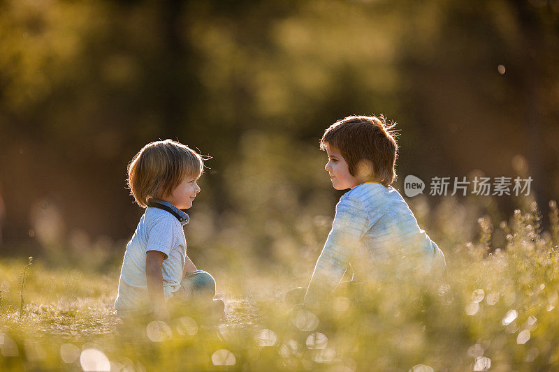 两个小男孩在草地上休息，互相聊天。
