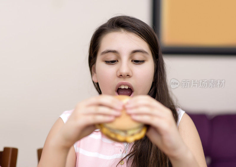 小女孩在室内吃汉堡