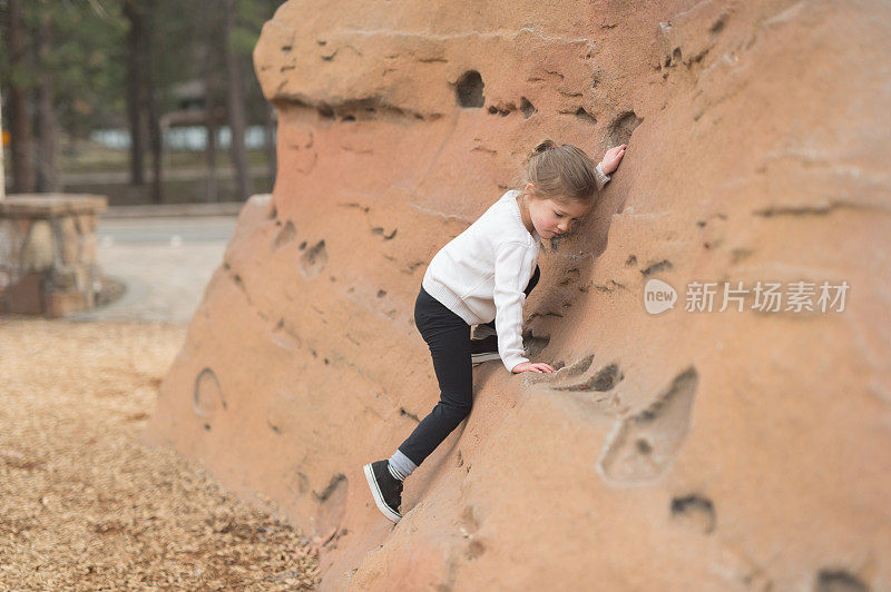 小女孩在操场上爬岩石