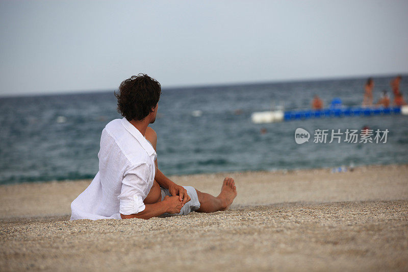 年轻人躺在沙滩上晒太阳，看着大海