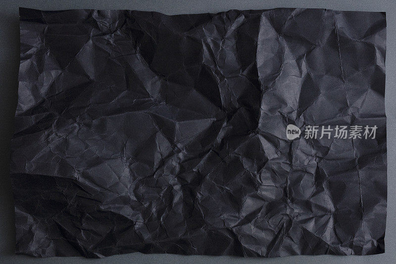 灰色背景上的皱黑纸