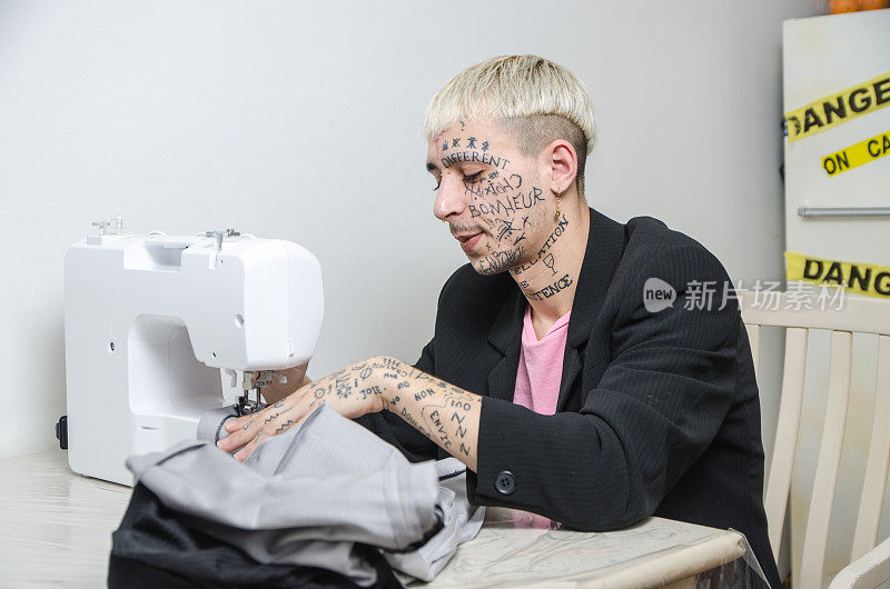 年轻的纹身男子在缝纫机旁