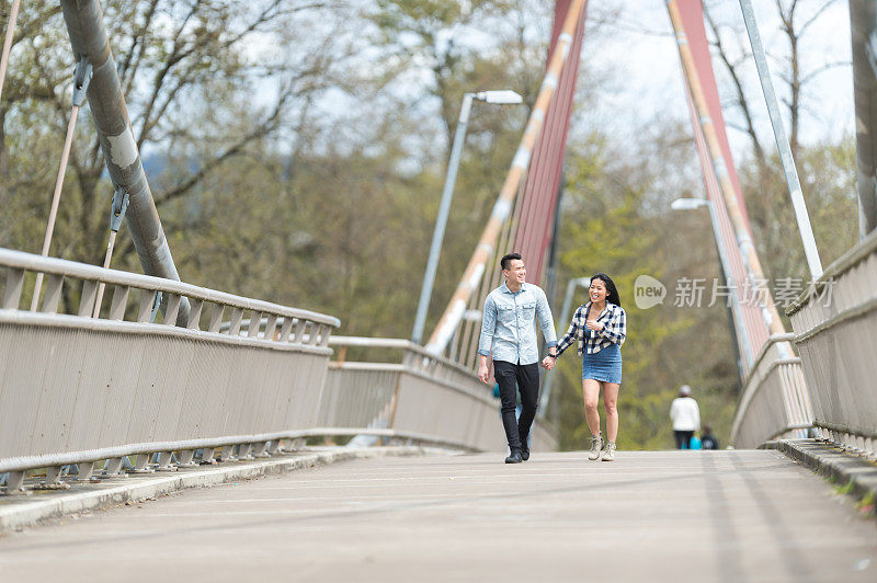 大学时代的亚洲夫妇手牵手过桥