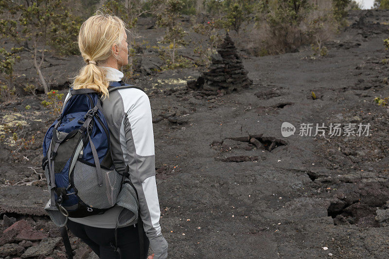 女性徒步旅行者沿着火山熔岩向前走