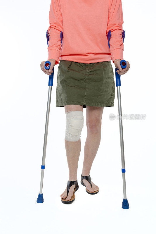 膝盖受伤的妇女拄着拐杖走路