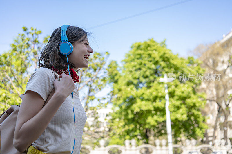 迷人的潮女人戴着耳机在城市里听音乐