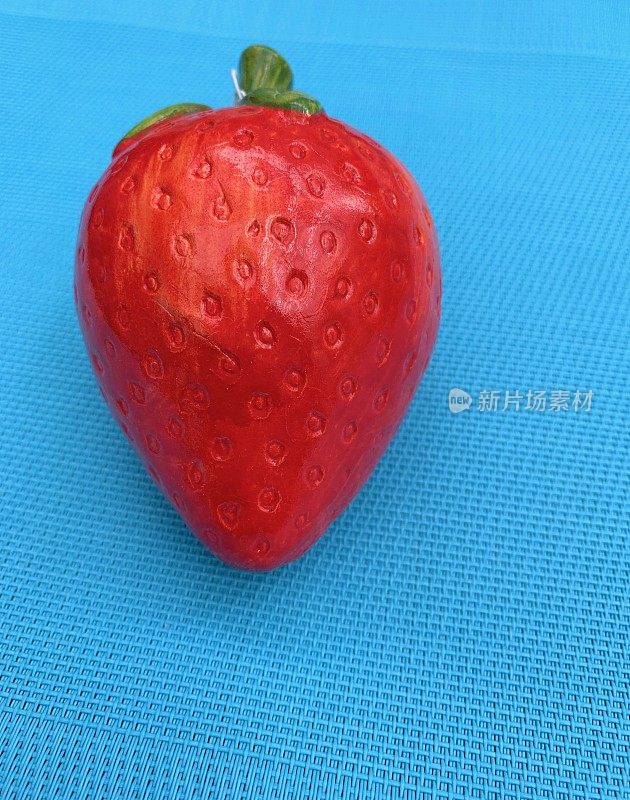 蓝色背景上的单个人工草莓