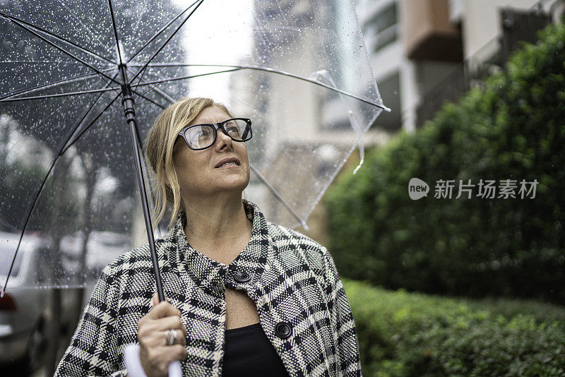 成熟的女人在户外用雨伞看向别处