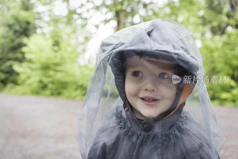 红发小男孩戴着蚊帐在露营地里玩耍