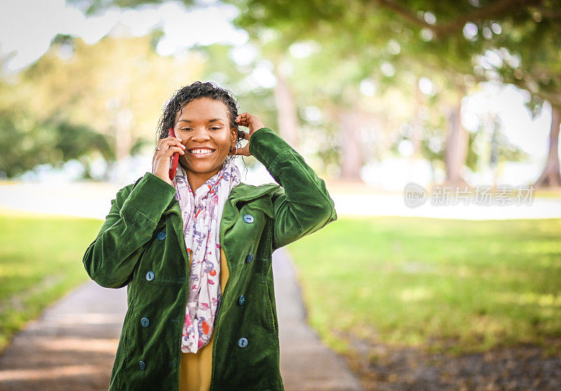 非裔美国妇女穿着薄夹克在户外使用手机