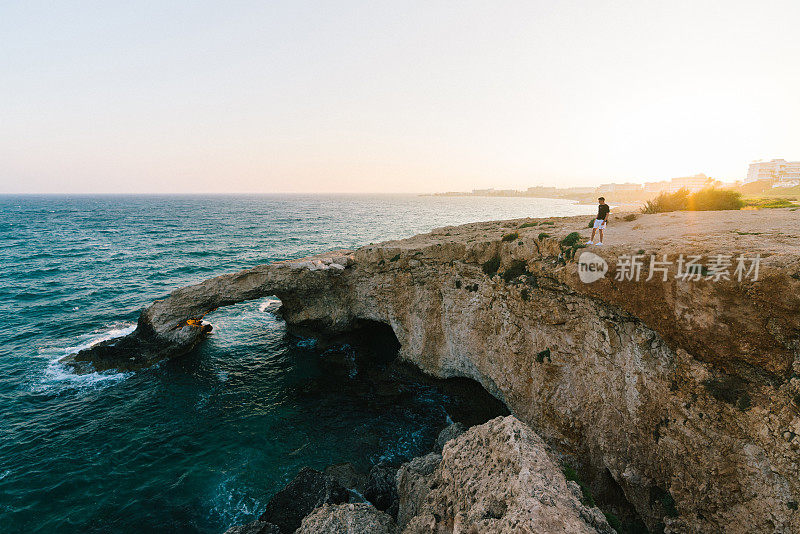 一个人站在悬崖上，看着塞浦路斯的海边