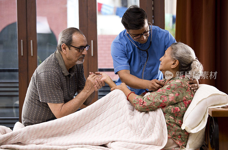 家庭护理人员在床上用听诊器检查老年妇女