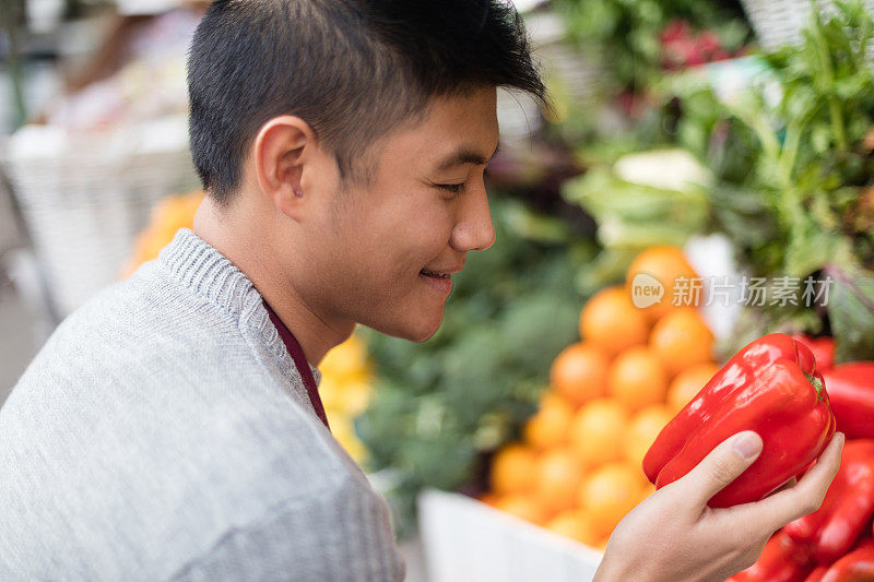 亚洲年轻人选择新鲜水果在杂货店