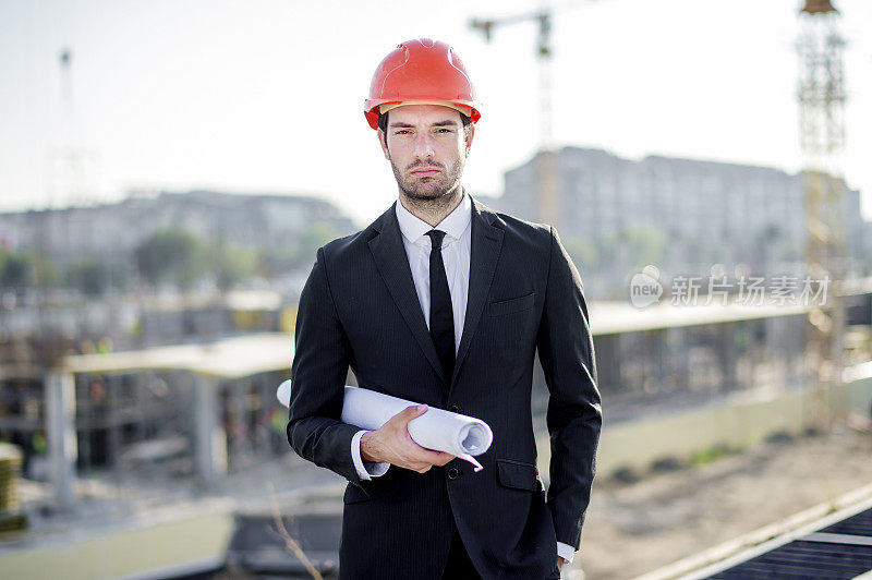 年轻的建筑工程师带着工程和安全帽