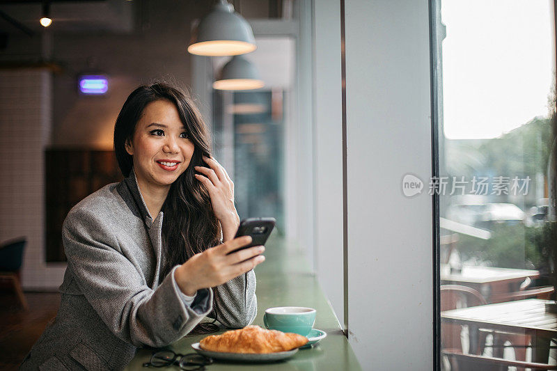 美女在智能手机上发短信，喝咖啡