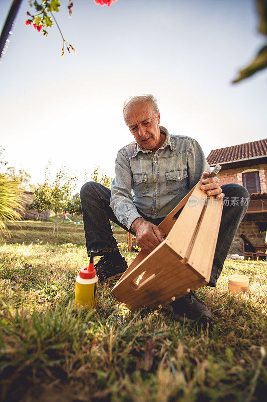 一个年老的木匠正在做一个木盒子