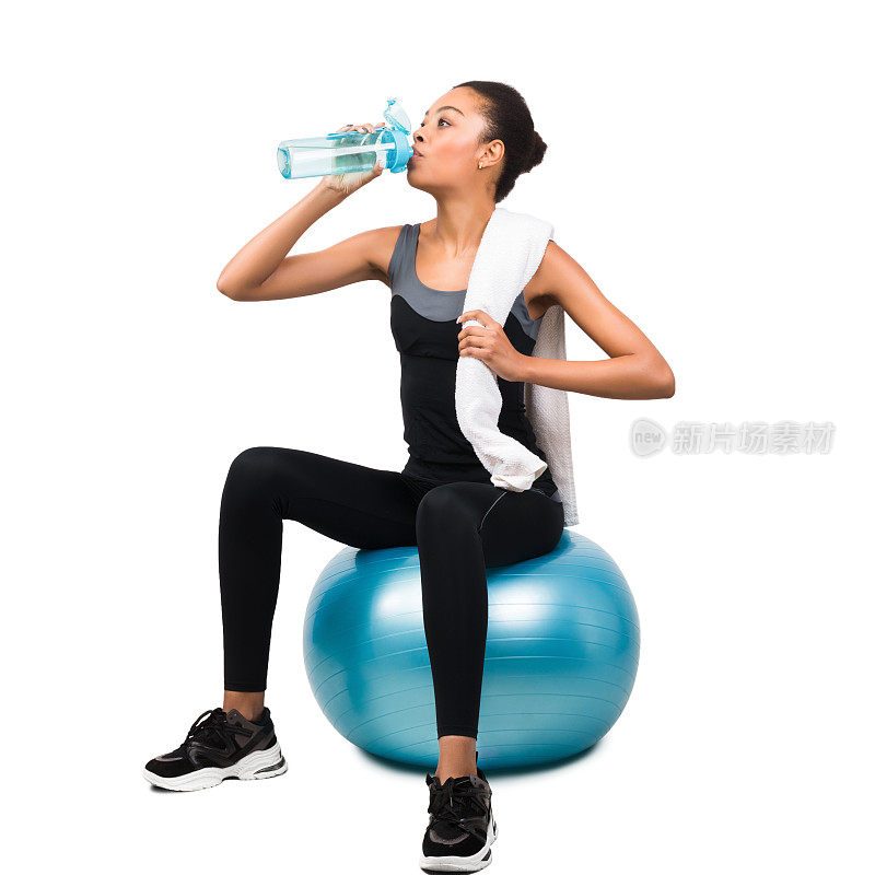 非裔美国女孩坐在健身球上喝水，白色背景