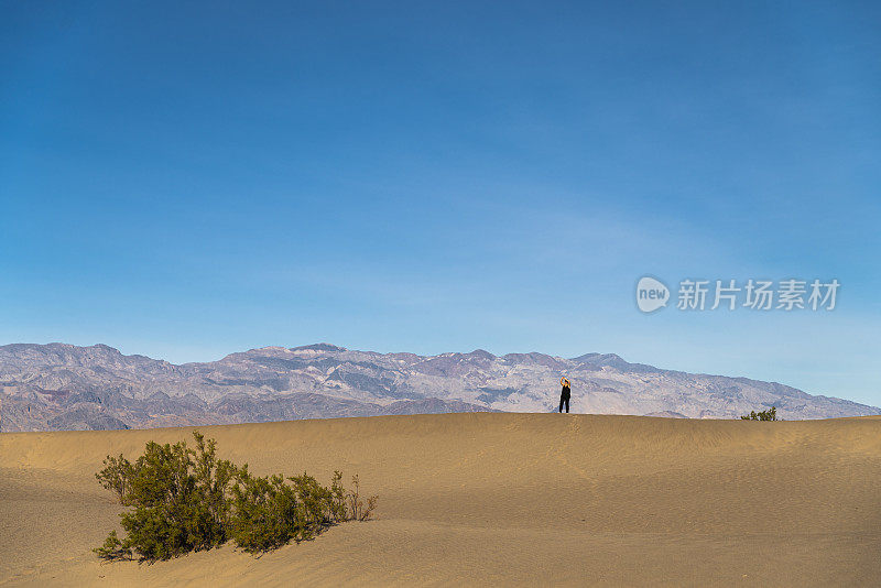 在加州死亡谷梅斯奎特平原的沙丘上徒步旅行的妇女。