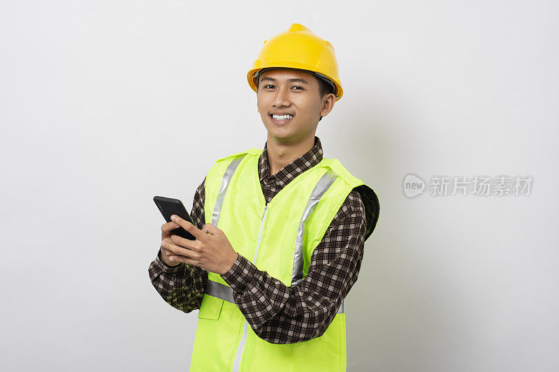 年轻的亚洲建筑工人微笑快乐使用智能手机隔离在白色背景