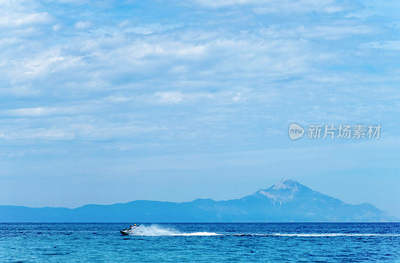 在阿索斯山的背景下，水力摩托车在蓝色的海水中飞驰