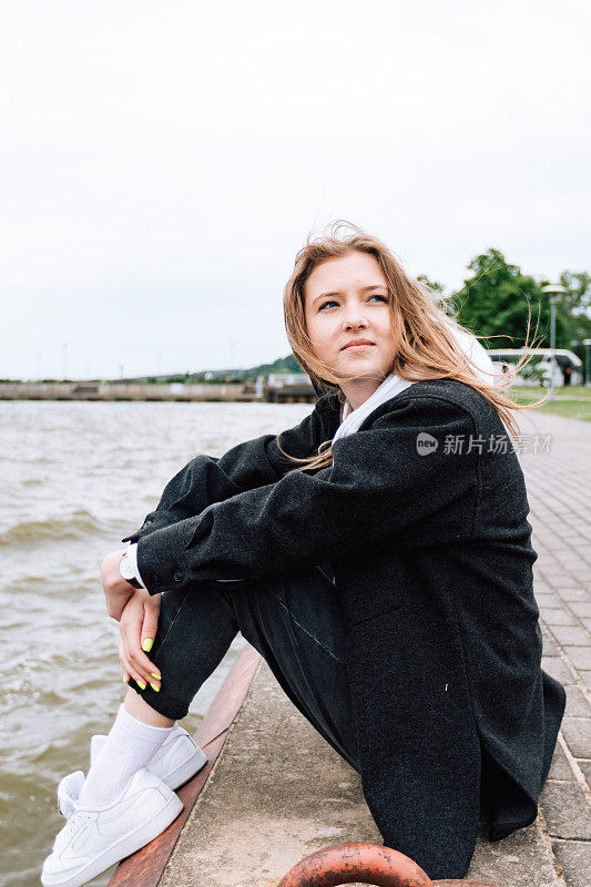 美丽的白人妇女户外的女性肖像，在海滩上享受大海。真实人物的生活方式摄影。女孩穿黑色休闲服装。