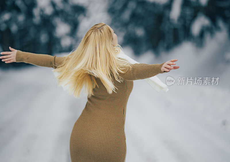 女人伸开双臂，享受着雪景