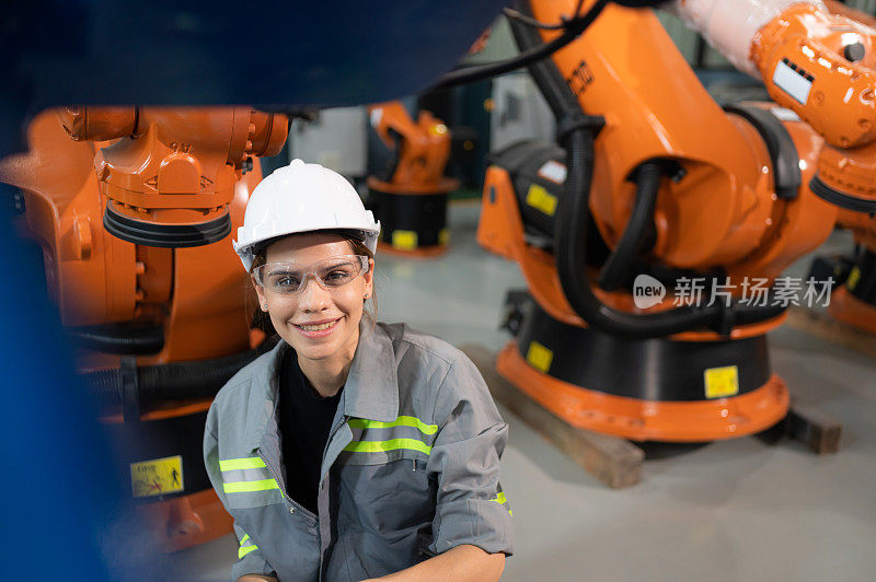 一名女工程师在机器人仓库的机器人手臂上安装程序。并在送机给客户前进行操作测试。
