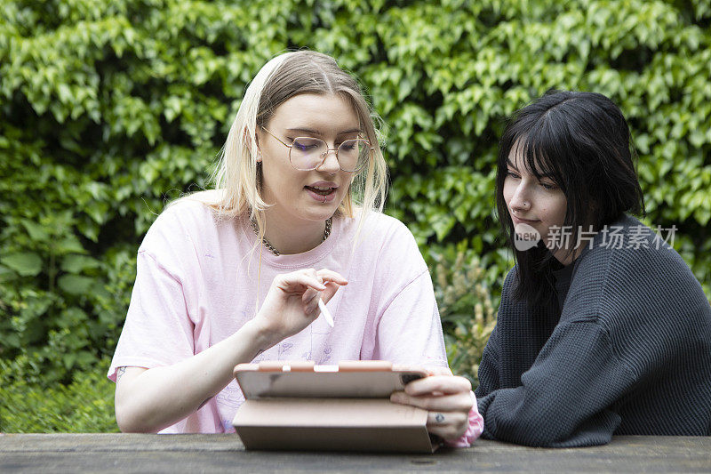 Z世代的女性朋友在花园里看着数码平板电脑
