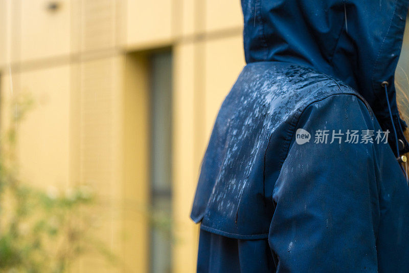 一个穿着蓝色雨衣的女人站在雨中。