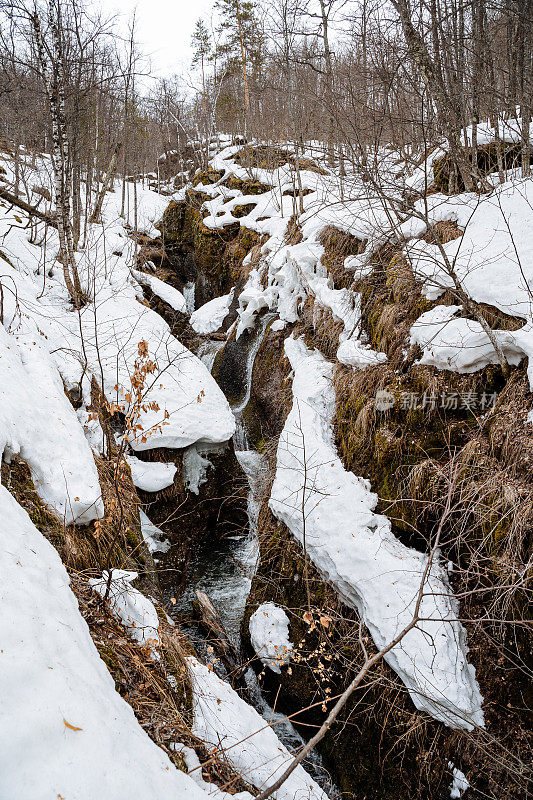 在森林中有瀑布的峡谷，一条山涧溪流落入山的裂缝，雪躺在峡谷的边缘，春天融化在森林中，Kungurtuy瀑布巴什科尔托斯坦俄罗斯