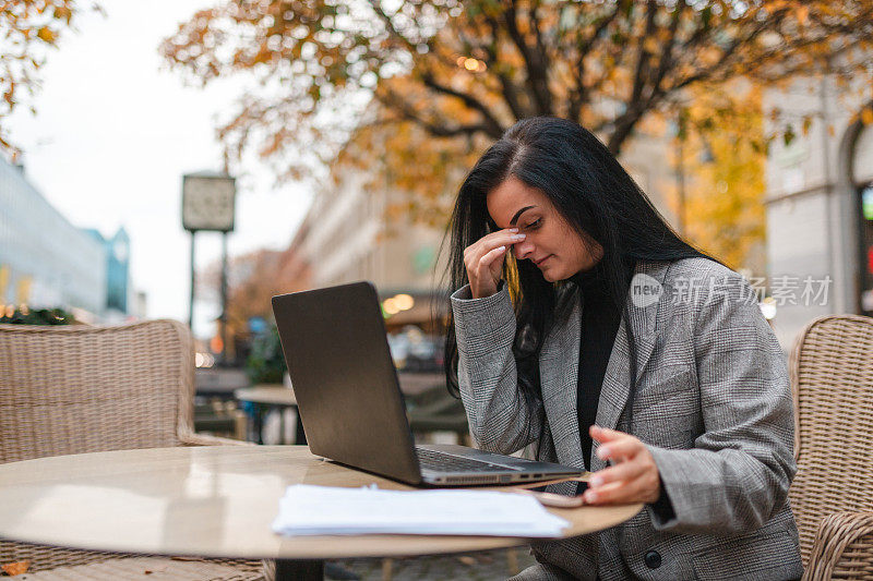 一位压力很大的年轻女商人坐在市中心的咖啡馆里用笔记本电脑工作