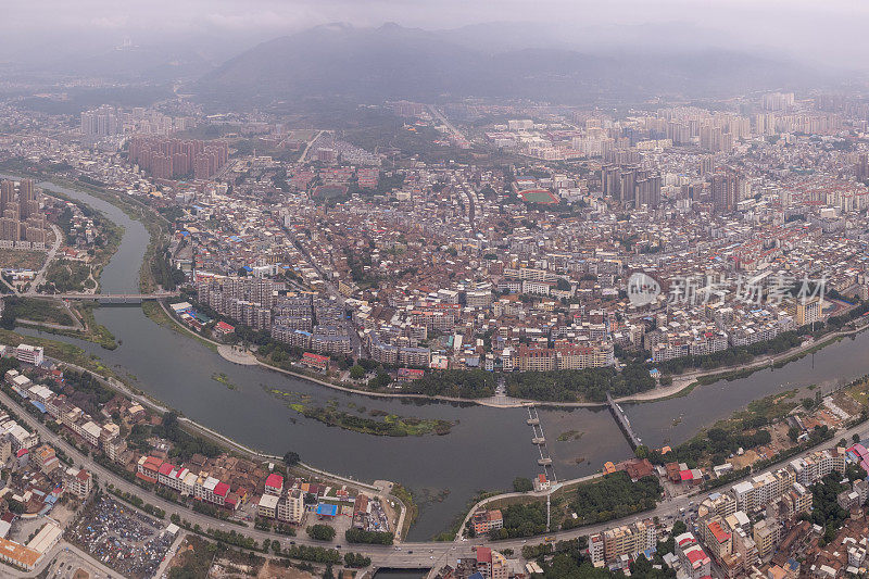 多云天，有河流的城市中人口密集的建筑物鸟瞰图