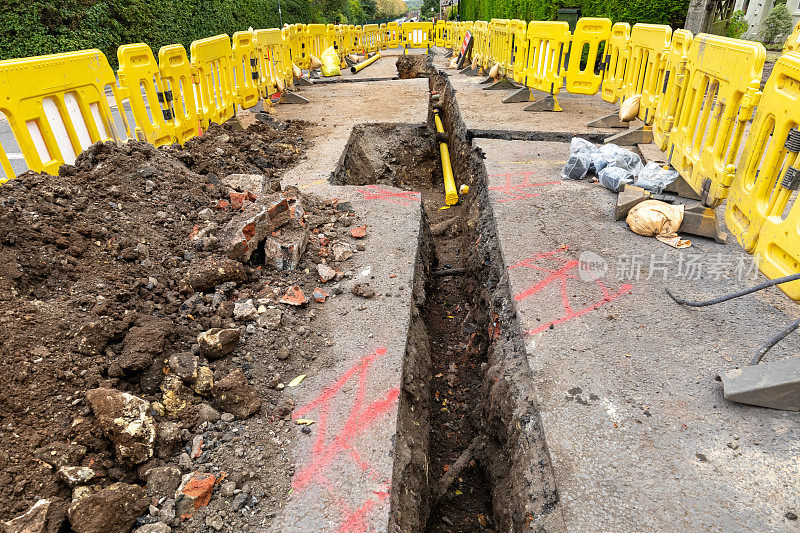 英国的道路工程正在挖掘当地的柏油路面，以修复地下的公用管道，并设置安全屏障和标志