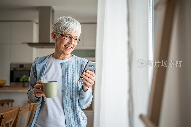 一位领取养老金的老妇人在家里用智能手机上网或通过即时通讯应用与朋友聊天