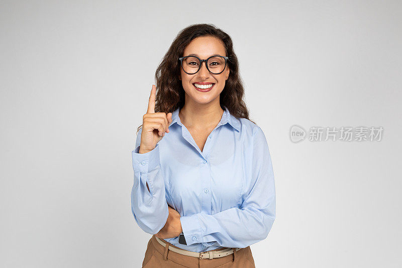 微笑自信的千禧一代白人商务女士，穿着正装戴着眼镜的老师指着空余的空间