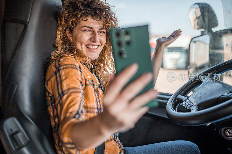 一位兴高采烈的女卡车司机用手机打视频电话，向她的朋友们展示她现在的位置