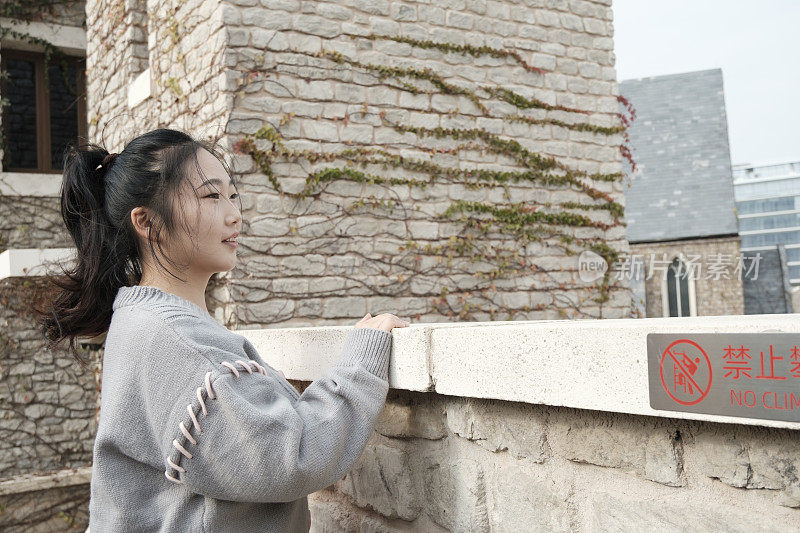 一个亚洲女人在复古的阳台上望向远方