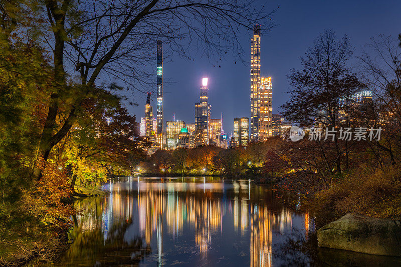 亿万富翁排的摩天大楼和夜晚中央公园湖的倒影。纽约曼哈顿
