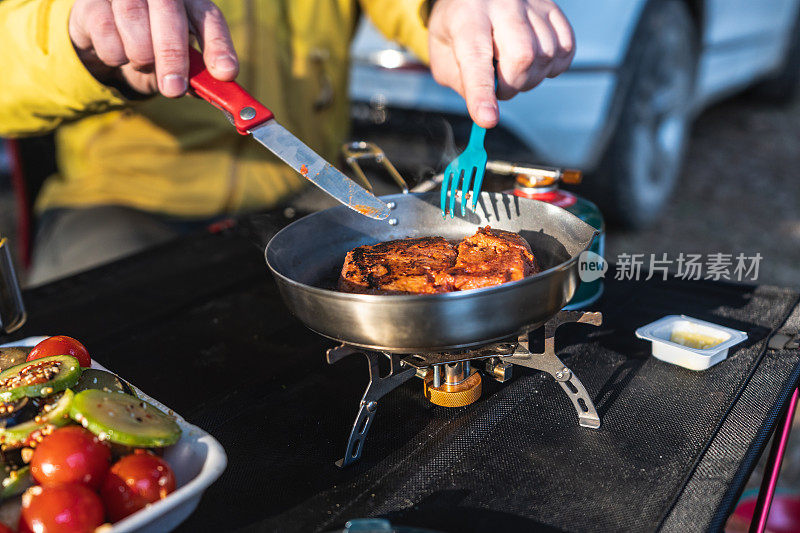 一名男子在森林中的露营地使用旅游燃烧器做饭