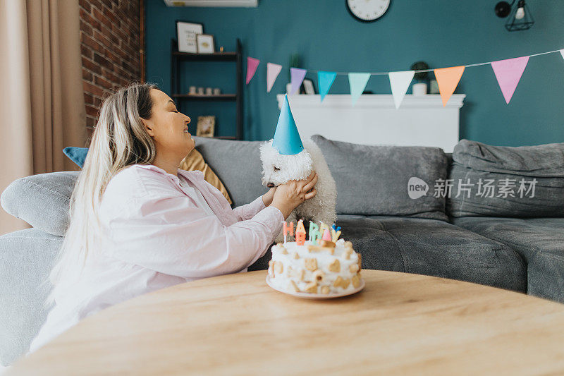 快乐的年轻女子在家里为她的狗庆祝生日