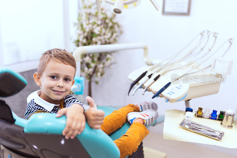 一个微笑的男孩坐在牙医的椅子上