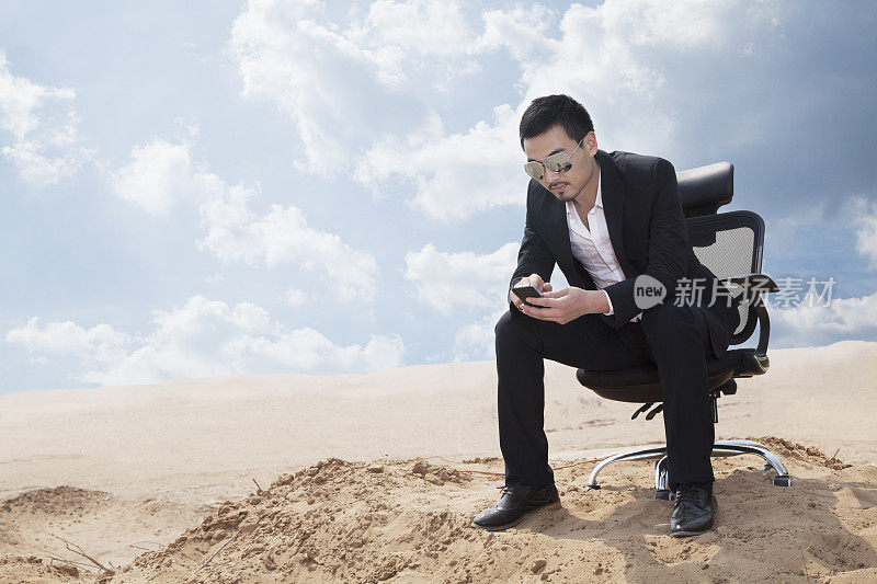 一个商人在沙漠中看手机，