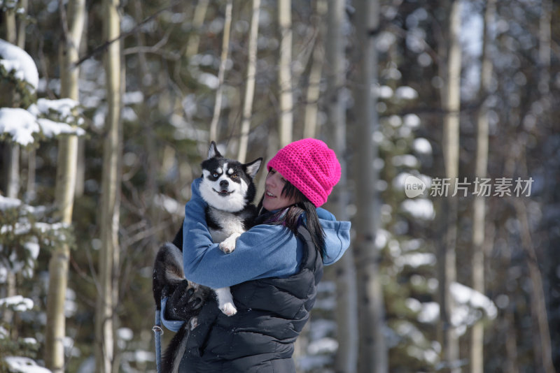 可爱的狗狗，傻乎乎的样子被迷人的户外女人在冬天抱着
