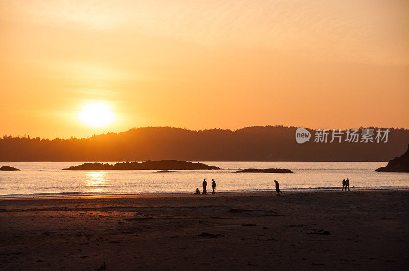 夕阳和橘色的天空，人们在海滩上散步